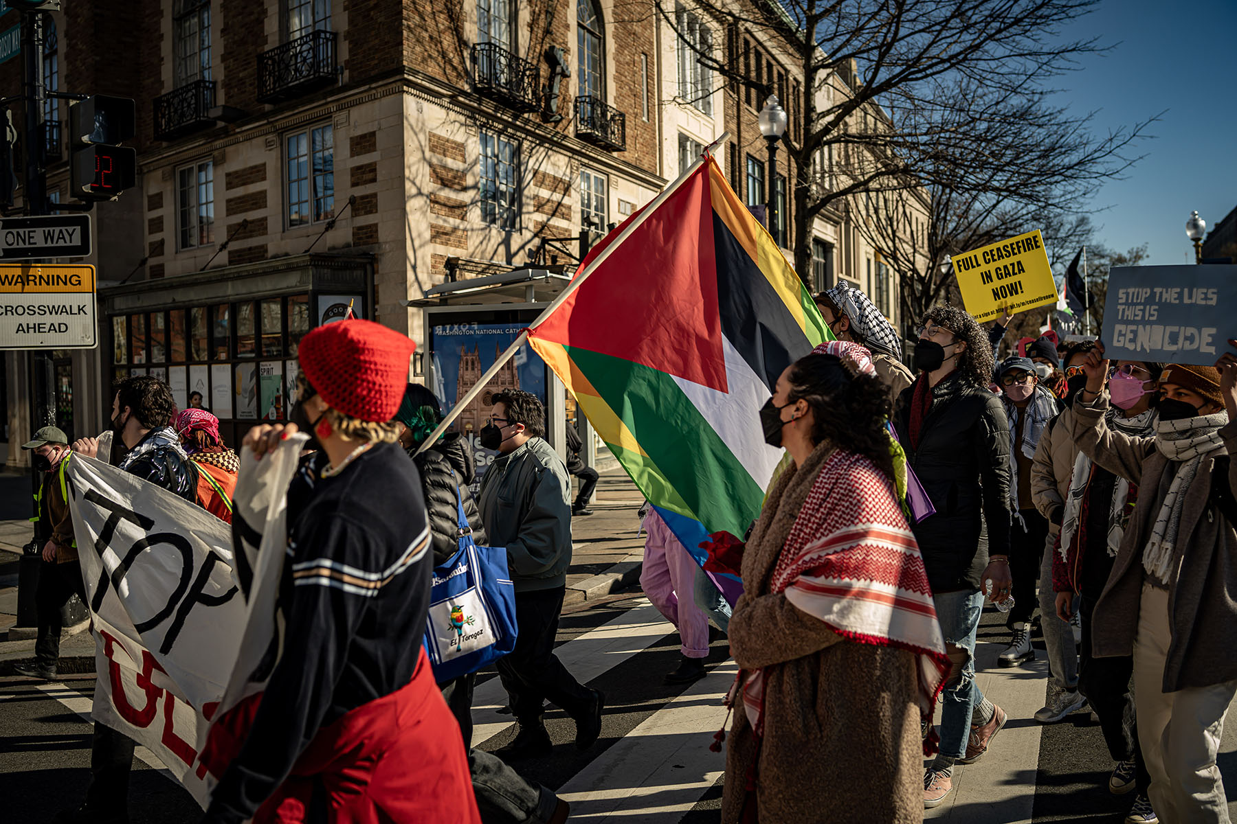 A coalition of queer and transgender Muslim and Jewish people, as well as LGBTQ+ Arabic hold placards and Palestinian flags demonstrate during a protest.