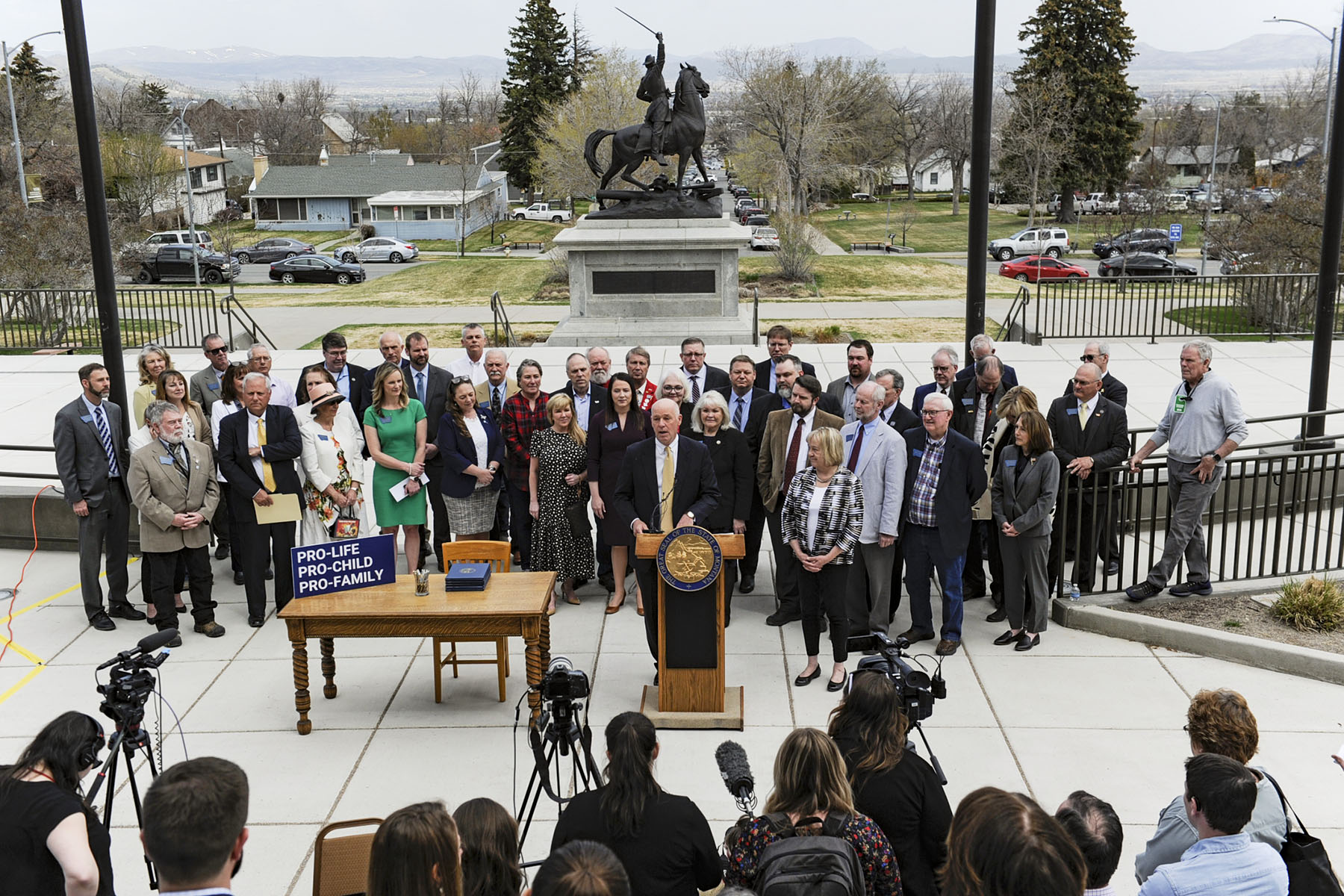 Gov. Greg Gianforte, surrounded by Republican lawmakers, speaks at a bill signing ceremony on the steps of the State Capitol.