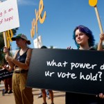 People hold signs referencing voting at a Women's March rally outside the State Capitol in Phoenix, Arizona.