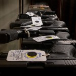 Semi-automatic firearms are displayed for sale on a shelf at a gun store.