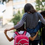 A mother walks her two children to school.