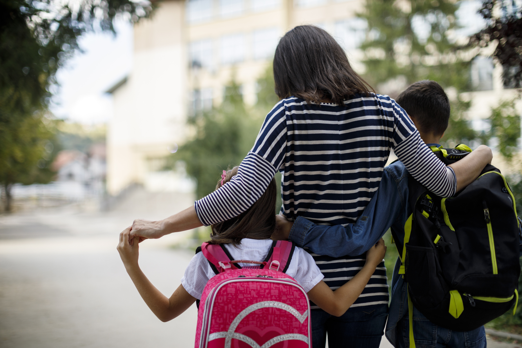 A mother walks her two children to school.