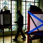 A silhouetted voter casts their ballots at a polling location in Arlington, Virginia.