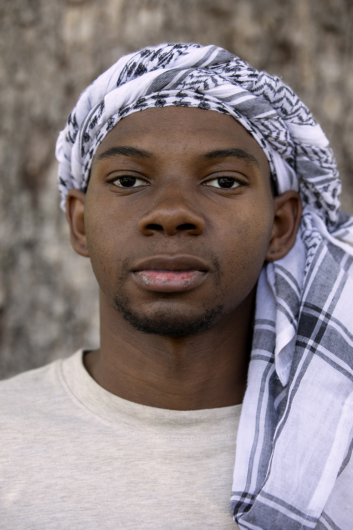 David Hunt poses for a portrait. He is looking at the camera and wearing a keffiyeh around his head.