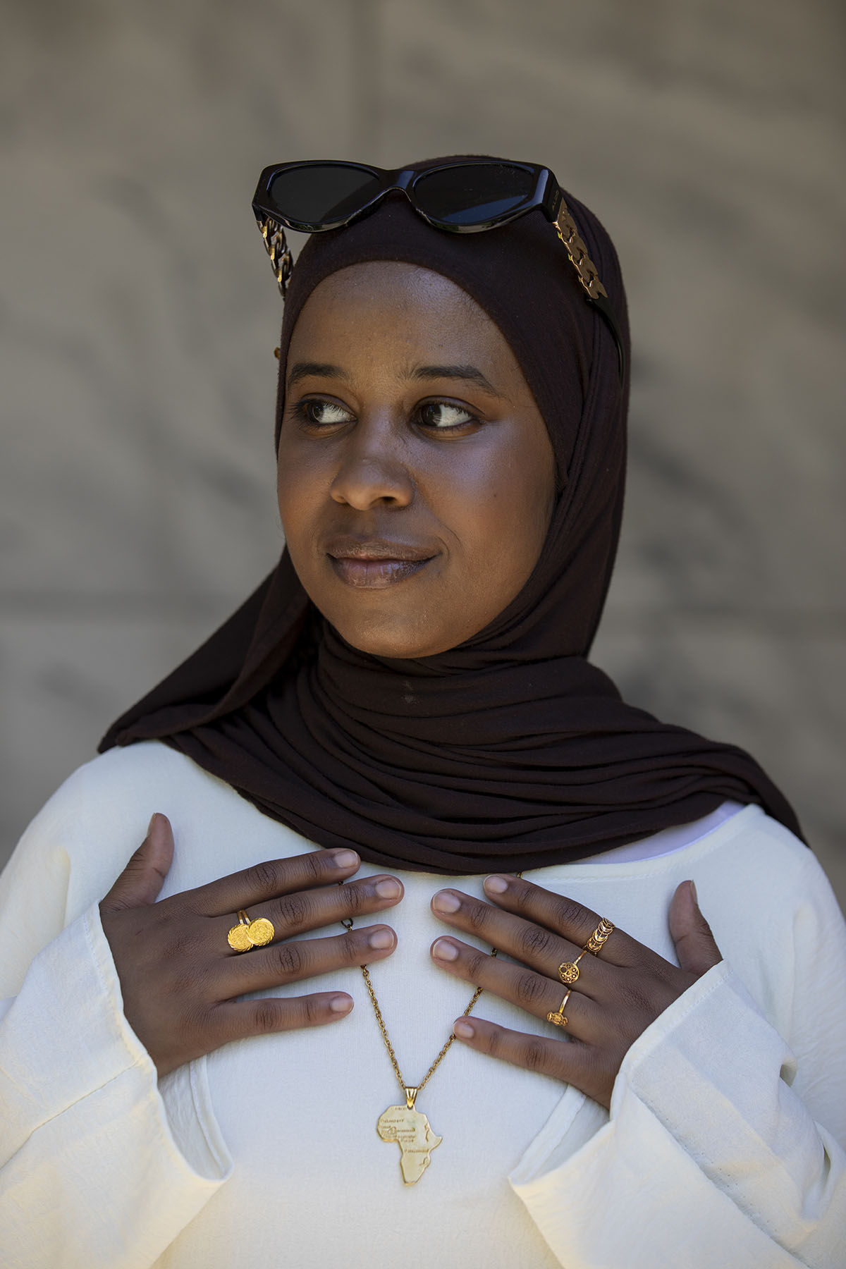 Maysam Elghazal shows off a gold necklace in the shape of Africa poses for a portrait