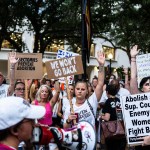 Abortion rights advocates rally as they raise their hands and hold signs at an overnight sit-in.