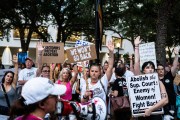 Abortion rights advocates rally as they raise their hands and hold signs at an overnight sit-in.