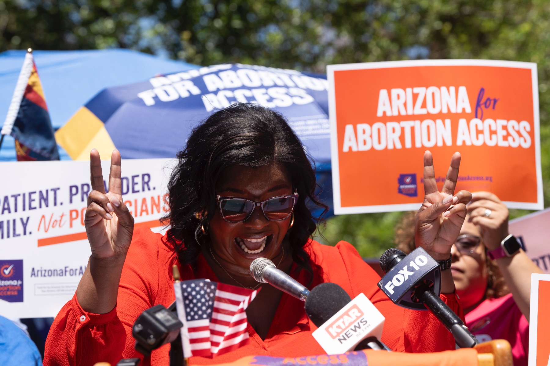 Chris Love of Arizona for Abortion Access speaks, flanked by people holding signs that say Arizona for Abortion Access