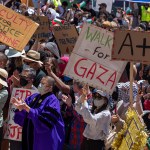 Pro-Palestinian demonstrators hold a student-faculty rally at an encampment on the UCLA campus. Signs read 