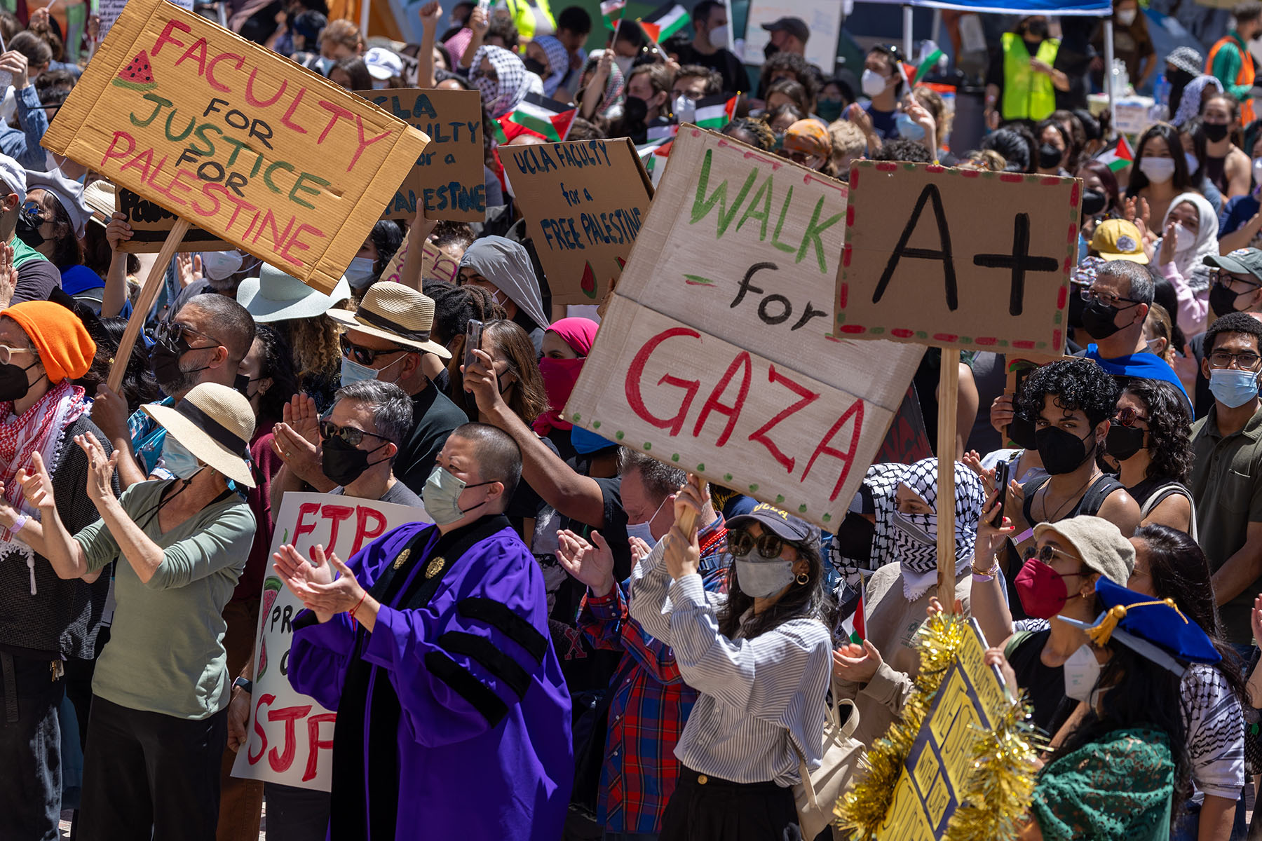 Pro-Palestinian demonstrators hold a student-faculty rally at an encampment on the UCLA campus. Signs read "Faculty for Justice for Palestine," "Walk out for Gaza," and "A+"