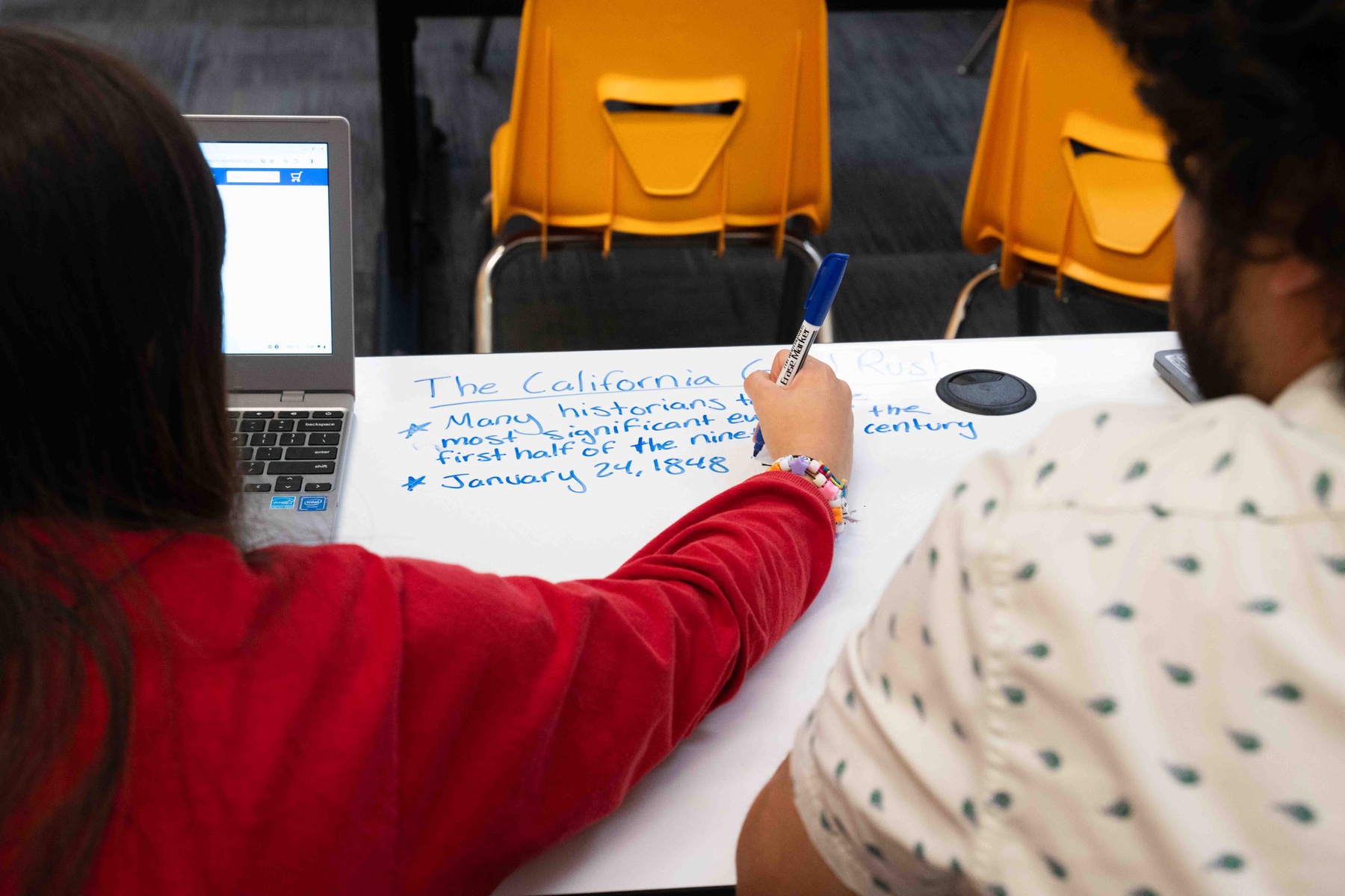 A woman works on a project on a table in a classroom.