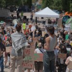 Two students (one draped in a kiffeh) and the other holding a bullhorn address student protestors at a pro Palestine protest at Occidental College.