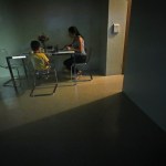 A woman sits with her son for dinner in their new, sparsely furnished apartment in New York.