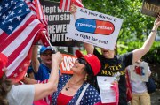 Protesters hold American flags and signs about Trump