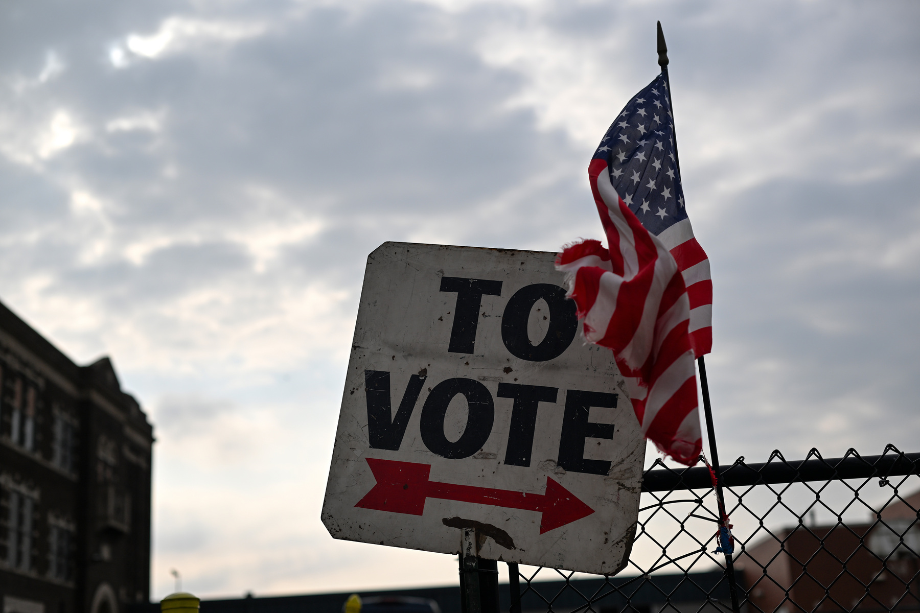 A vote sign and American flag are displayed outside a school.