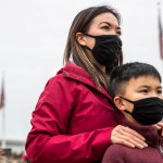 A mother stands behind her son as they attend a rally together.