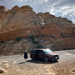 Drabinski stands next to a van in front of a large rocky formation.