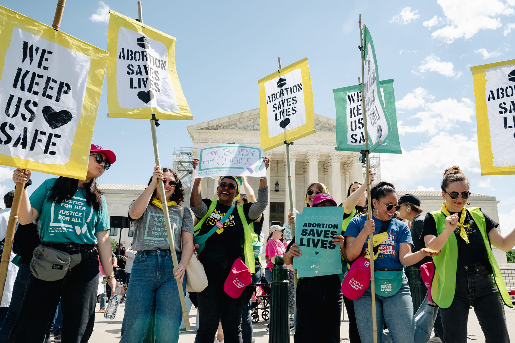 Abortion rights advocates protest outside the Supreme Court. They hold banners that read "Abortion saves lives" and "We keep us safe."