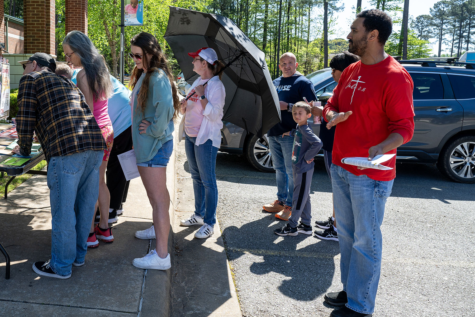 A volunteer with Progressive Arkansas Women holds an umbrella to block pro-life supporters as people sign petitions at a petition signing event.