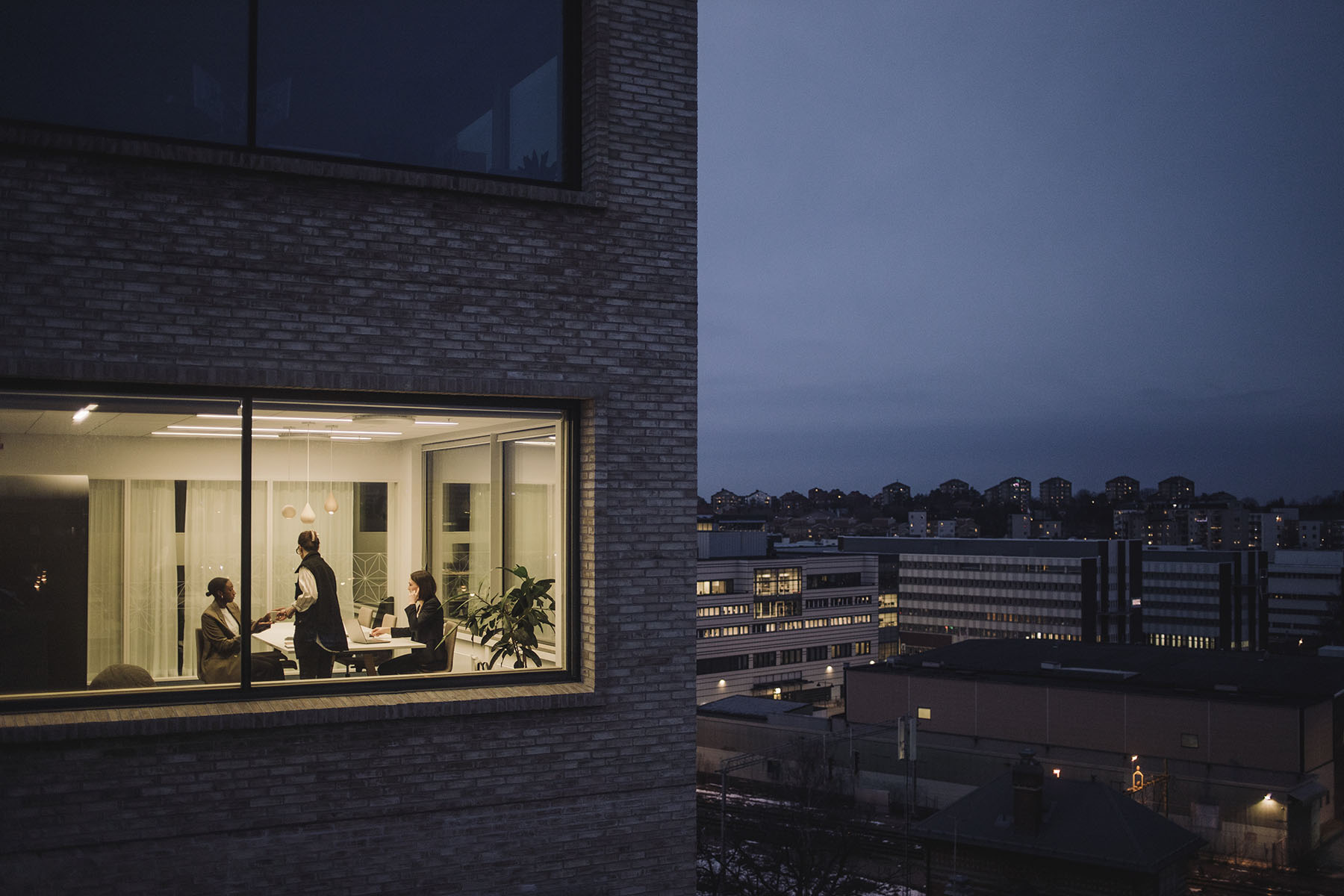 Multiracial female colleagues working late seen through window of work place.