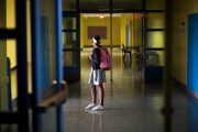 A girl stands in school hallway.