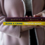 A woman holds Beloved by Toni Morrison and Born a Crime by Trevor Noah.