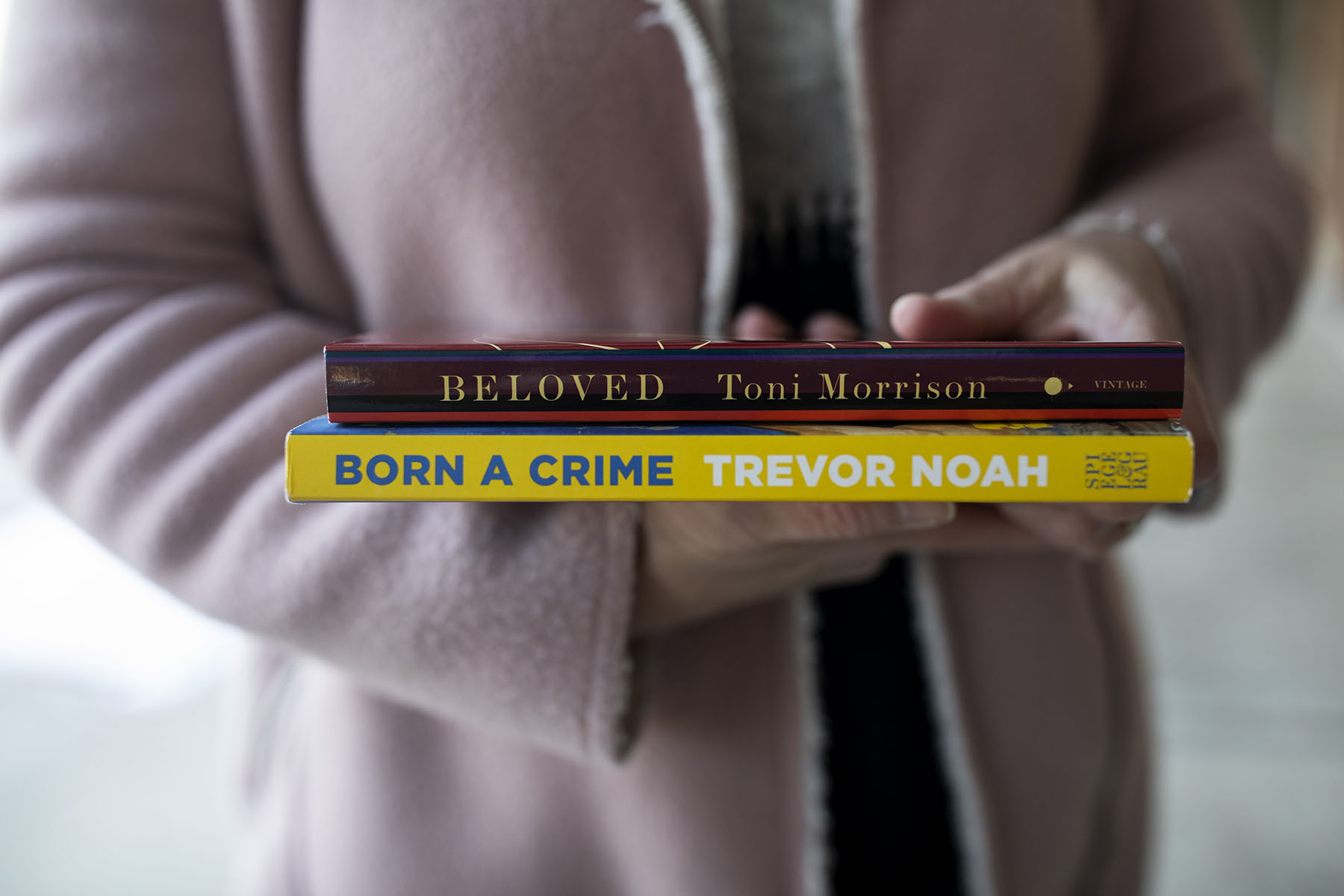 A woman holds Beloved by Toni Morrison and Born a Crime by Trevor Noah.