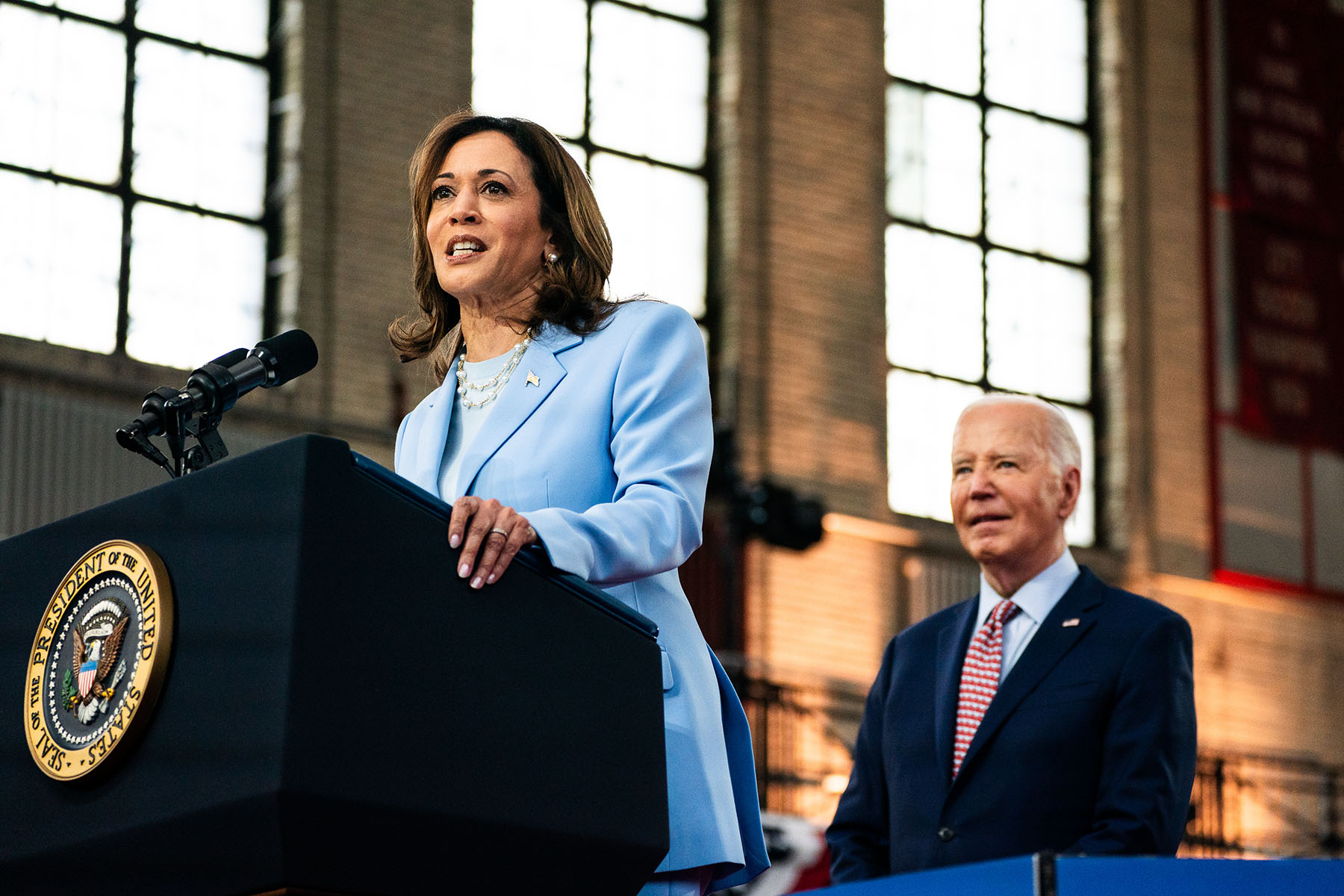 Vice President Kamala Harris speaks at a campaign event at Girard College in Philadelphia. President Biden stands behind her and smiles.