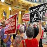 People holding anti-abortion signs at the Iowa Capitol.