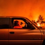 A woman holds her head while evacuating her home as the Park Fire rages in Tehama County, California.