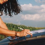 A women engineer works in the field, inspecting wind turbine efficiency.