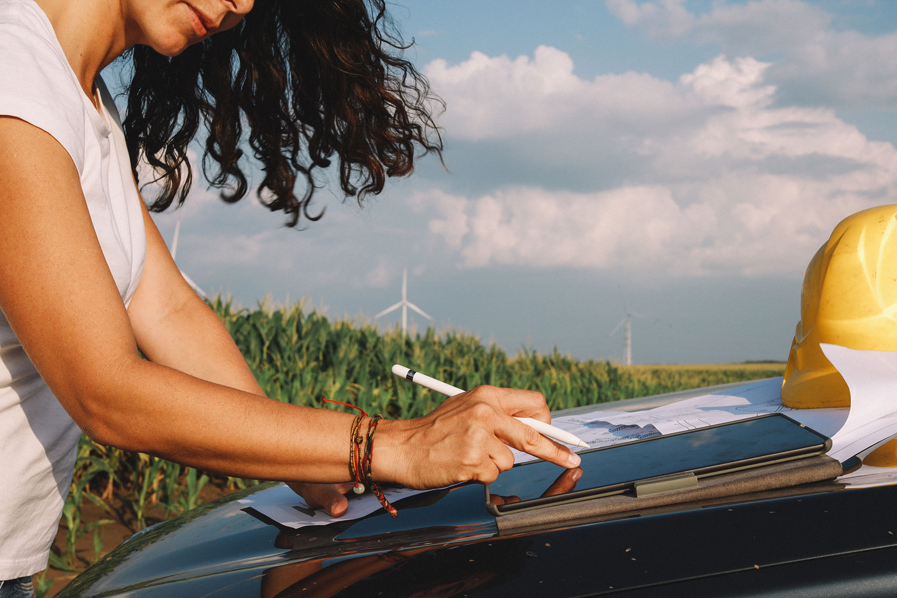 A women engineer works in the field, inspecting wind turbine efficiency.