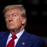 A portrait of Donald Trump, who is wearing a blue suit, red tie and an American flag pin.