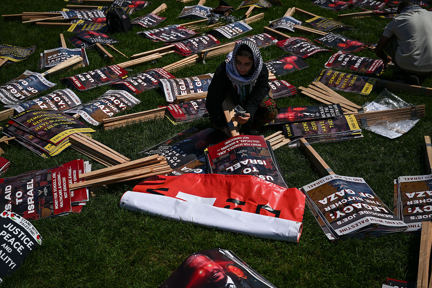 A demonstrator organizes protest signs in a park.