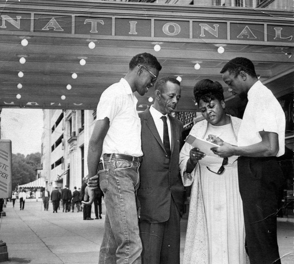 A three quarter length portrait of civil rights leader Fannie Lou Harmer with three men