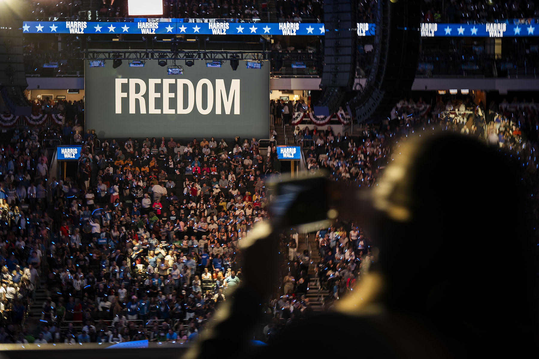 People pack the Fiserv Forum in Milwaukee, Wisconsin, for a campaign rally with Vice President Kamala Harris and her running mate. Above the crowd, a huge banner that reads "FREEDOM" hangs.