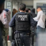 An ICE agent monitors asylum seekers being processed upon entering the Jacob K. Javits Federal Building in New York City.