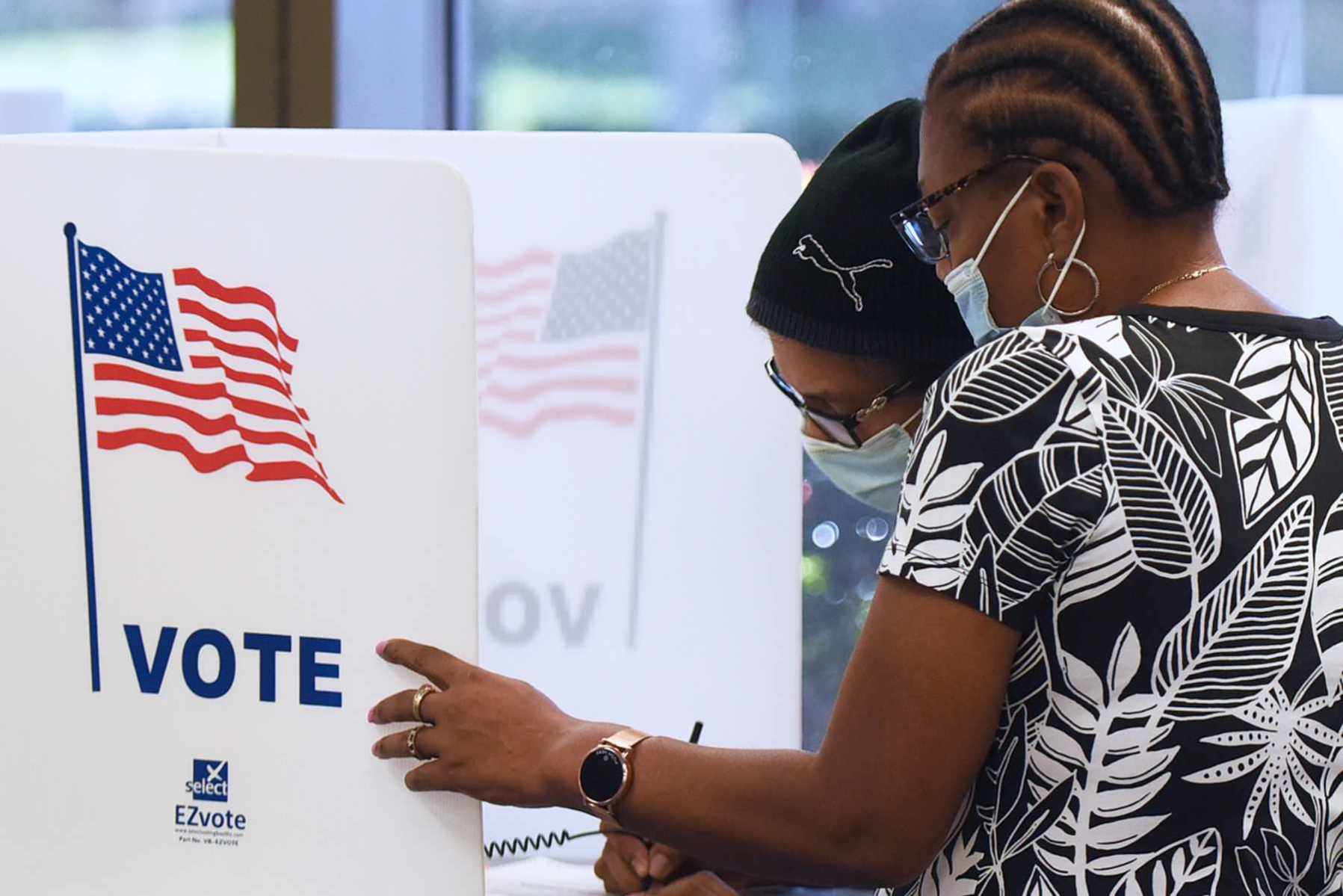 Women wearing face masks fill out vote-by-mail ballots at the Orange County Supervisor of Elections office on October 15, 2020 in Orlando, Florida.