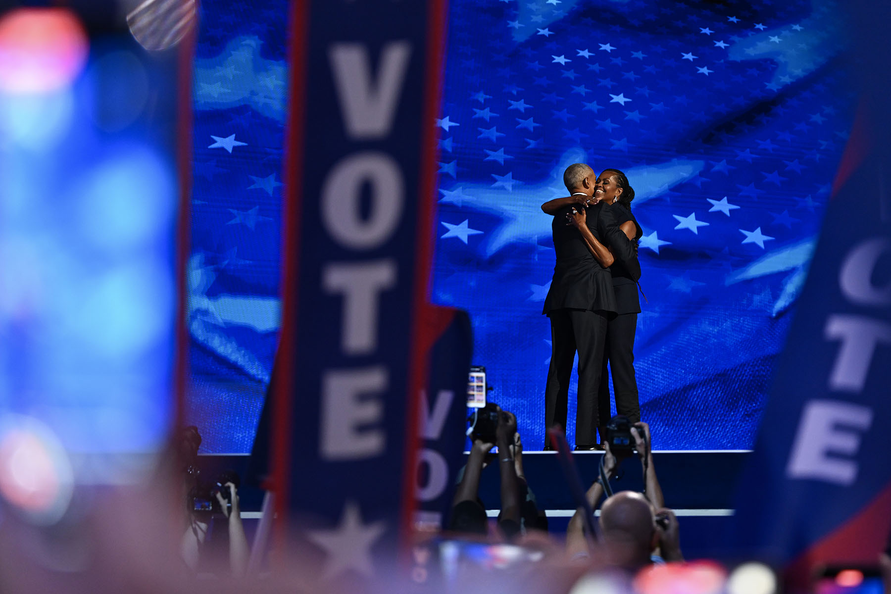 Former President Barack Obama hugs former first lady Michelle Obama as he arrives to speak on stage.