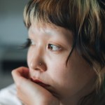 Close up shot of young asian nonbinary person with colorful hair looking away.