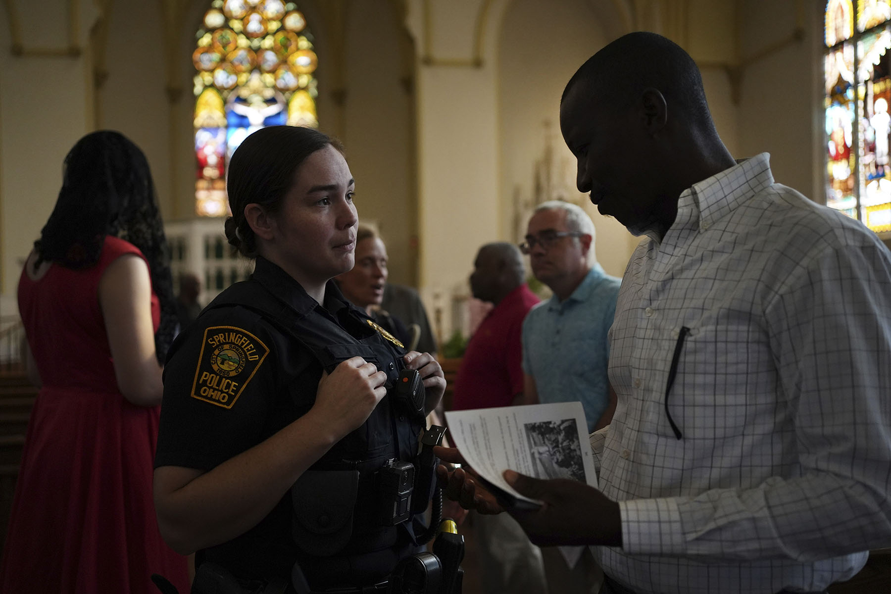 A Springfield police officer chats with parishioners after a service in support of the Haitian community at St. Raphael Catholic church in Springfield, Ohio.