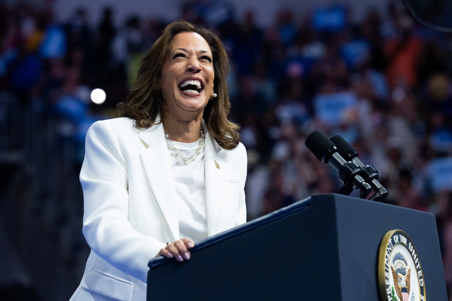 Vice President Kamala Harris, wearing a white suit and standing at a lectern and smiling, speaks in Savannah, Georgia