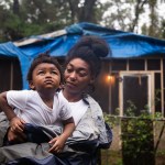 Janika Young holds her son A'King Hart, 2, in Tallahassee, Florida outside of their already damaged home.