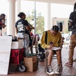 A student sits and fills out a voter registration form at a voter registration booth