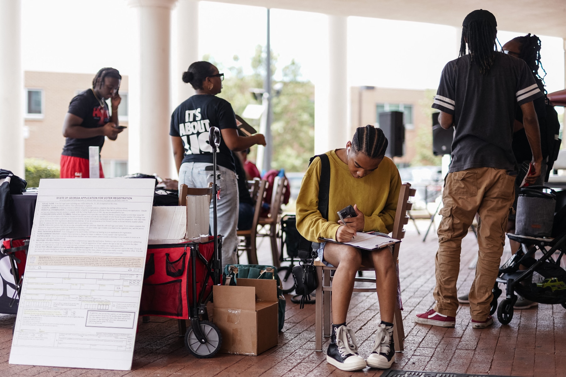 A student sits and fills out a voter registration form at a voter registration booth