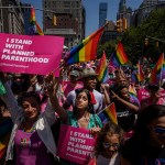 Participants holding pride flags and signs that read 