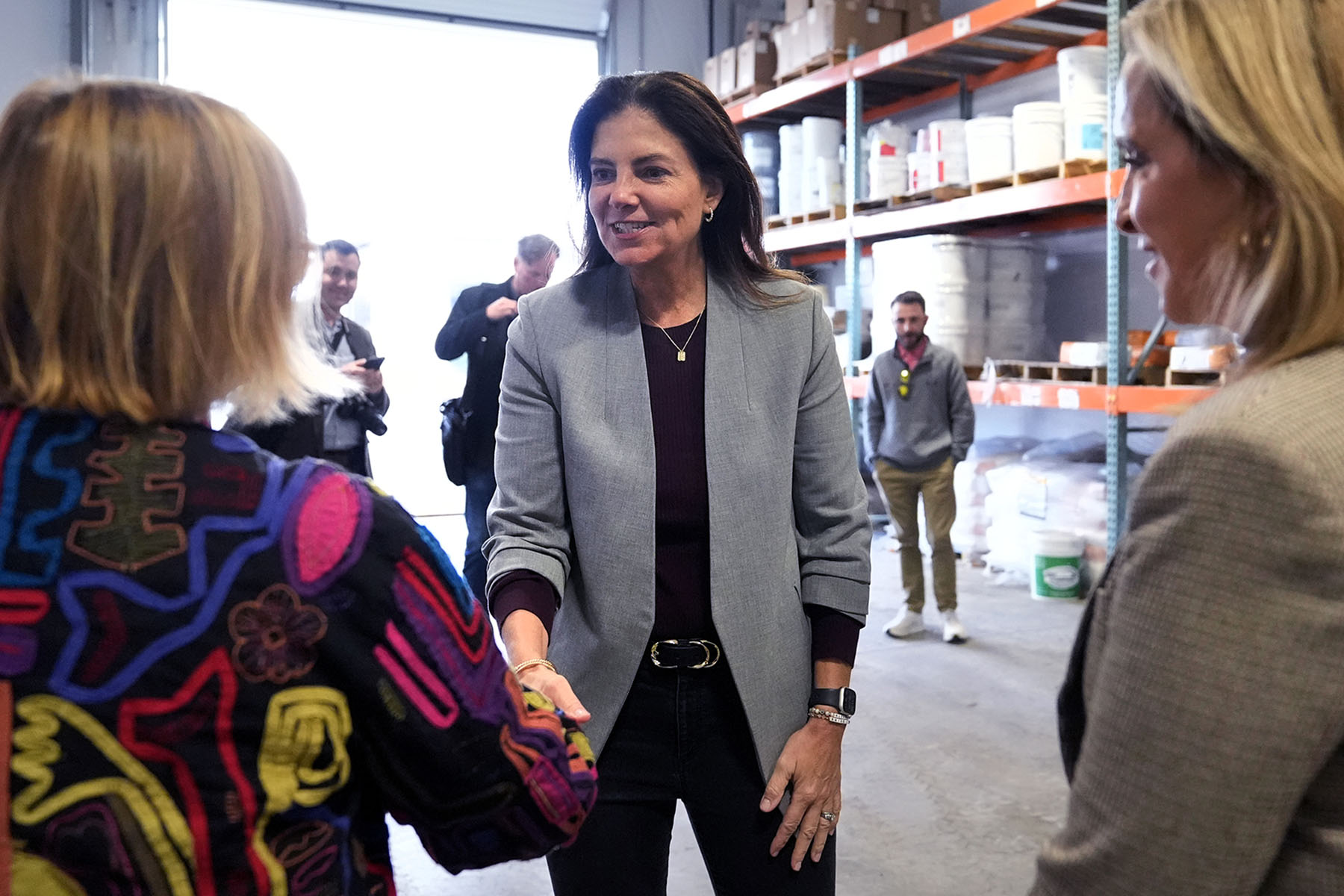 Republican gubernatorial candidate Kelly Ayotte shakes hands with administrators during a visit to a local concrete coating business.