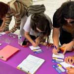 Several students lean over a table filling out voter registration forms.