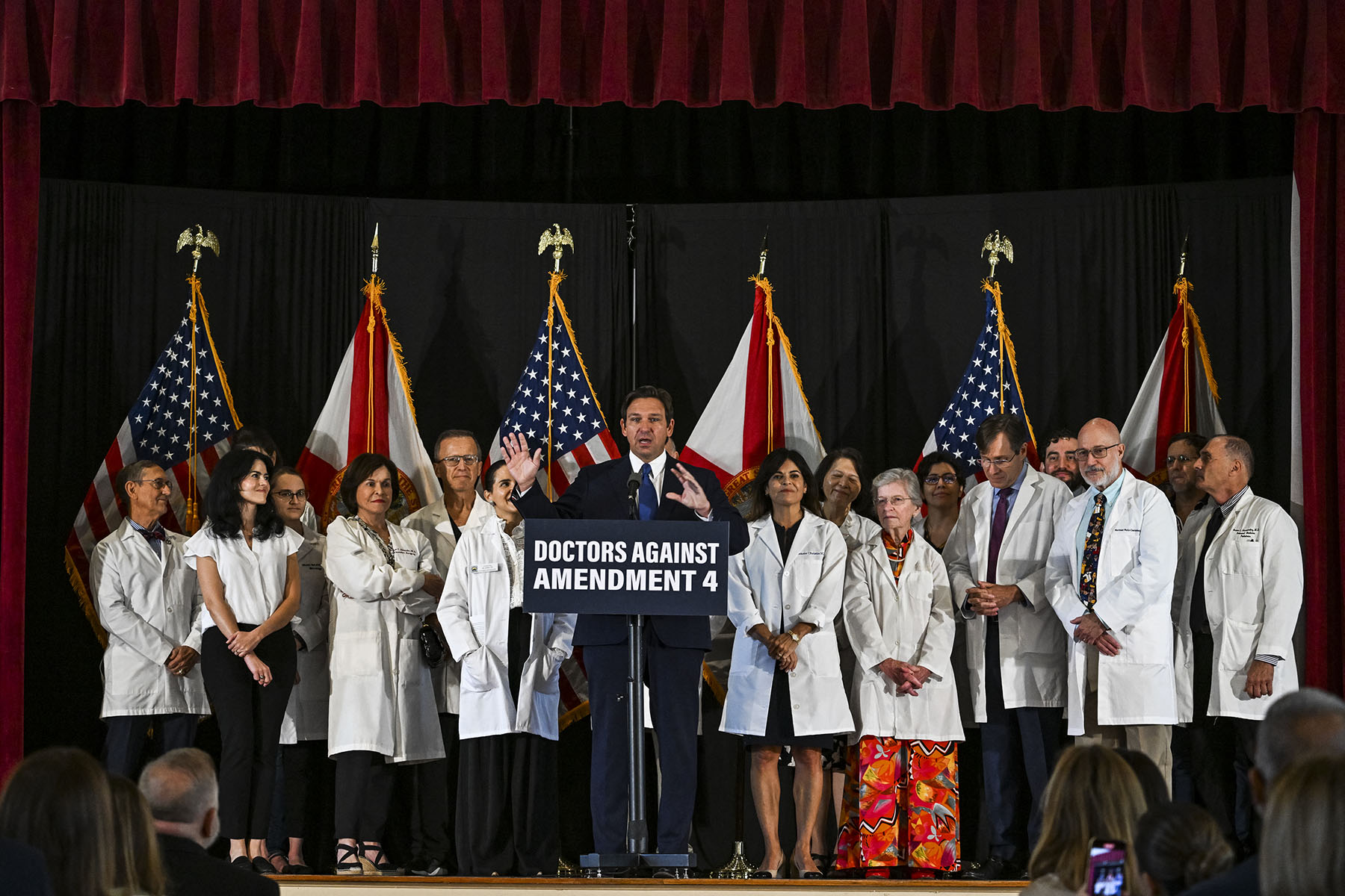 Florida Governor Ron DeSantis speaks onstage surrounded by people in white coats during an event with Florida Physicians Against Amendment 4 in Coral Gables, Florida.