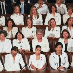 Four rows of women sit in Congress together, all wearing white.